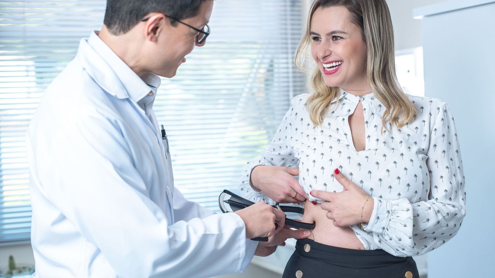 A physician taking a waist measurement during a medical weight management visit